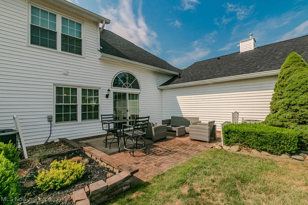 Back of house featuring a patio, outdoor lounge area, roof with shingles, and a chimney