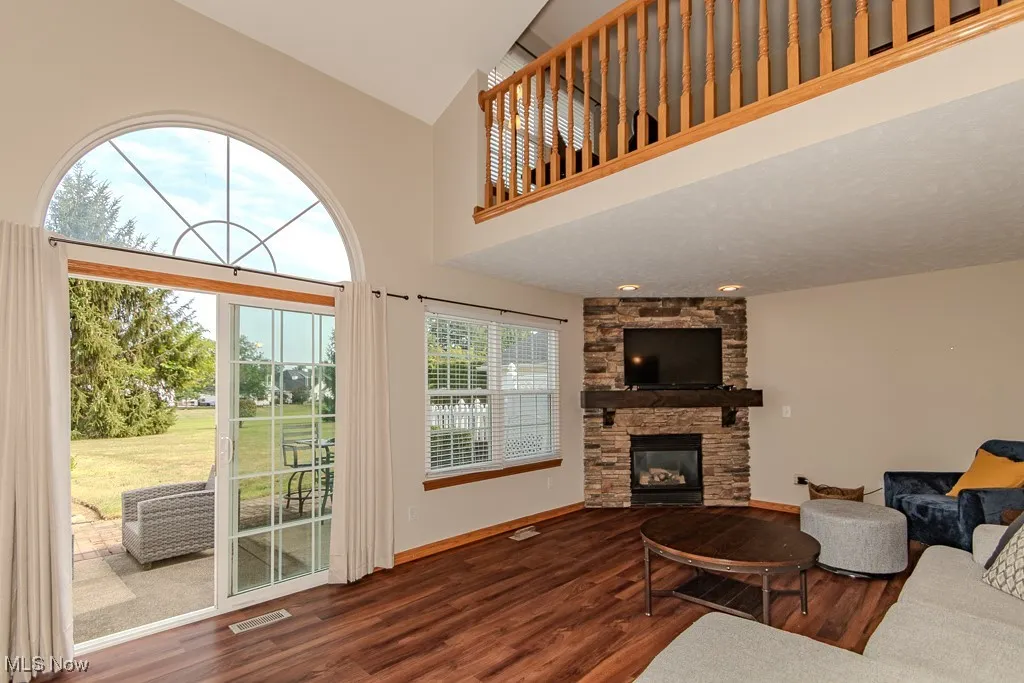 Living area featuring wood finished floors, a fireplace, and high vaulted ceiling