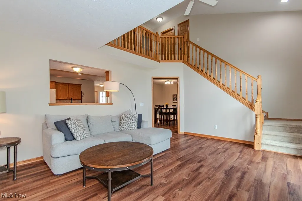 Living area featuring a high ceiling, wood finished floors, stairs, and a ceiling fan