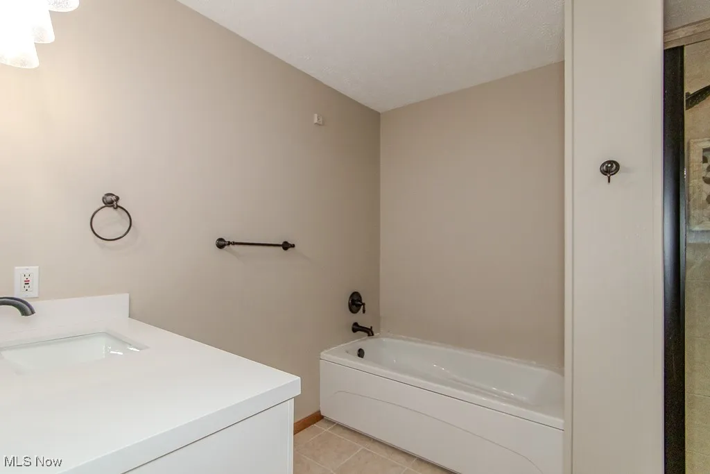 Bathroom with tile patterned floors, a bathtub, and vanity