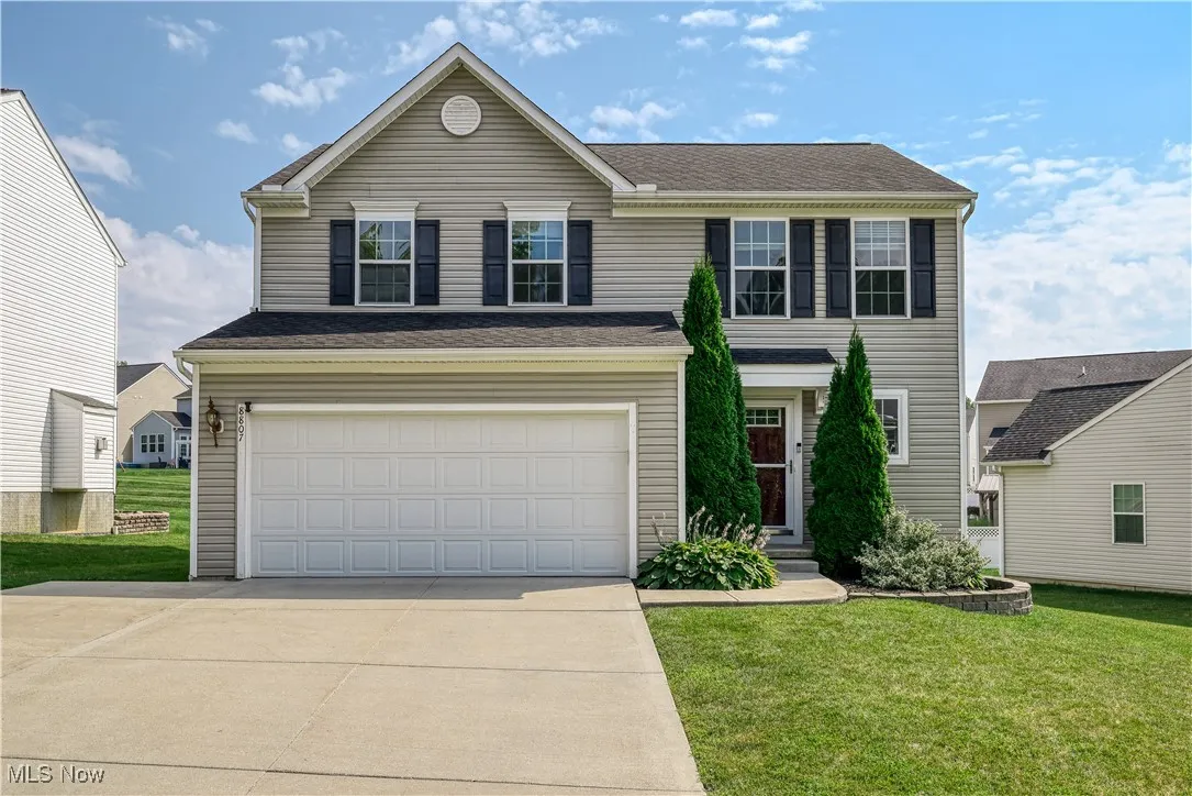 Traditional-style home featuring driveway, a front lawn, and an attached garage
