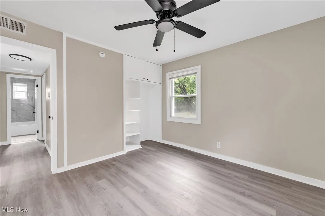 Unfurnished bedroom featuring multiple windows, light wood-style floors, a closet, and a ceiling fan