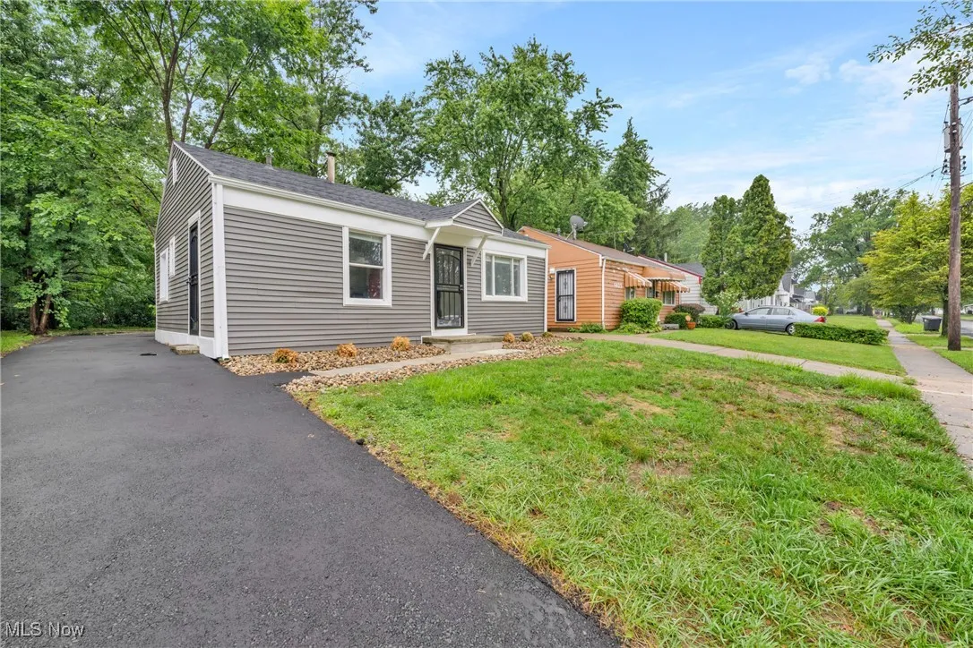 Ranch-style home with a front yard, roof with shingles, and asphalt driveway
