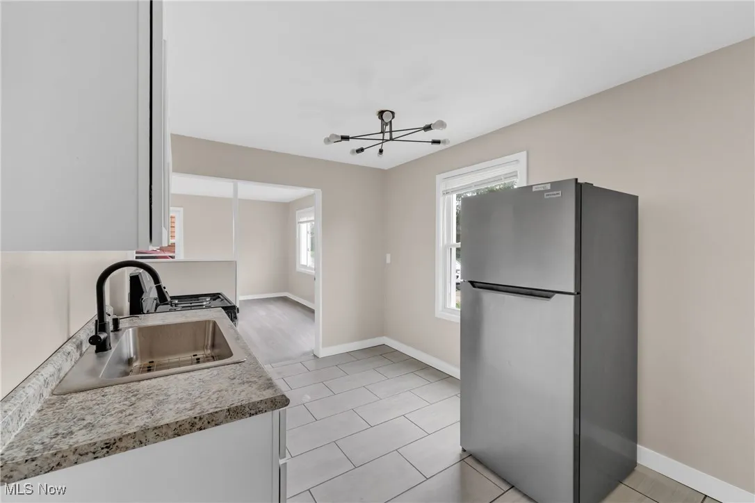 Kitchen featuring freestanding refrigerator, light countertops, light tile patterned floors, and a chandelier