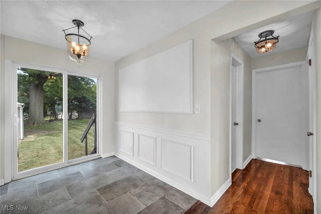 Unfurnished dining area featuring a chandelier and a decorative wall