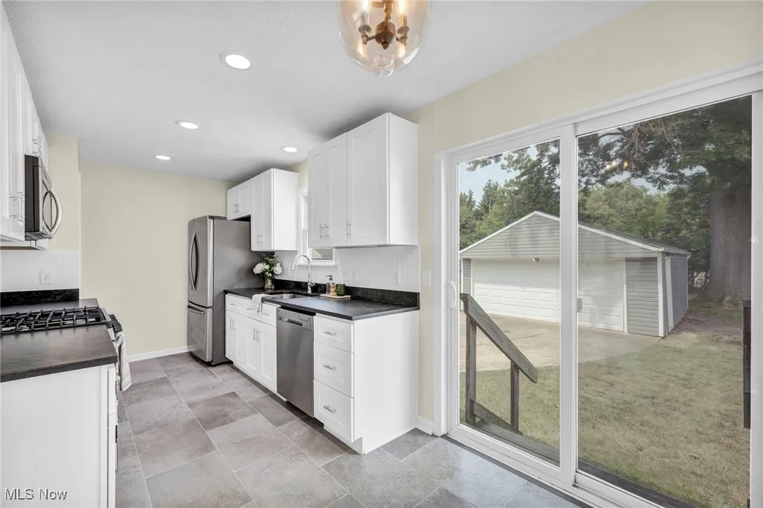 Kitchen with dark countertops, white cabinetry, stainless steel appliances, and recessed lighting
