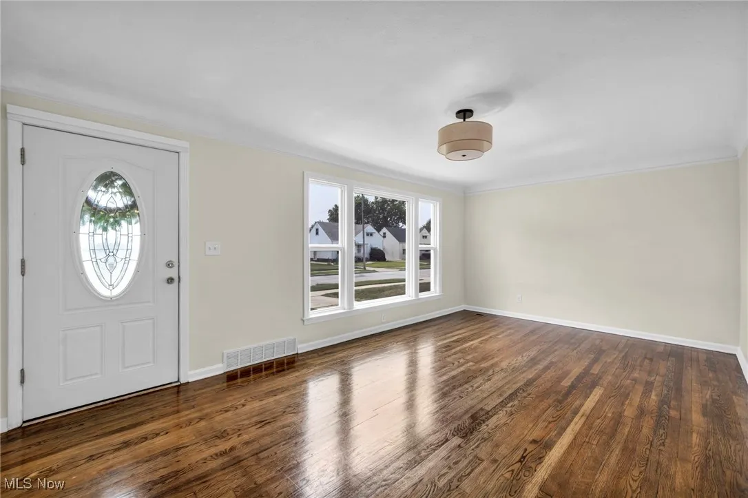 Foyer entrance featuring wood finished floors and ornamental molding