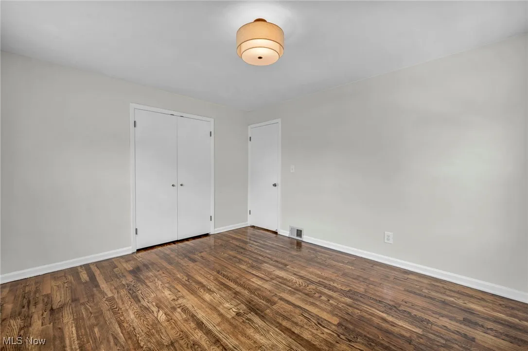 Unfurnished bedroom with dark wood-type flooring and a closet