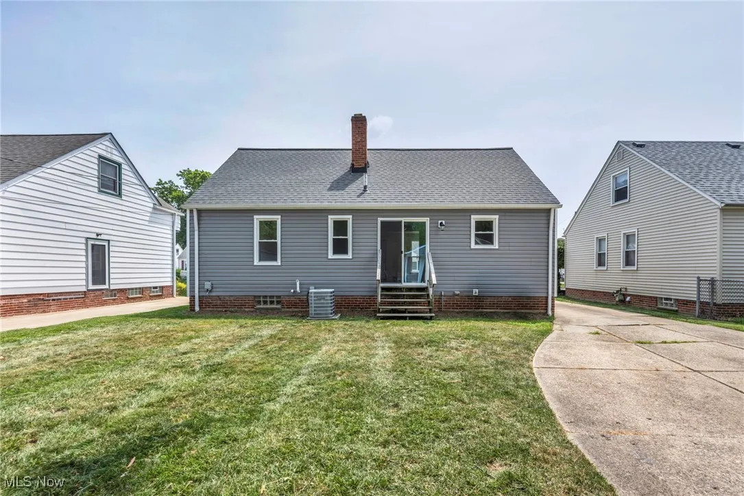 View of front of home featuring a chimney, a front lawn, and roof with shingles