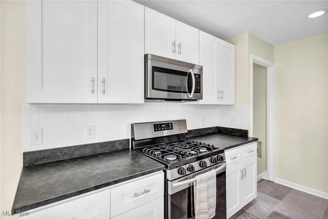 Kitchen featuring stainless steel appliances, dark countertops, and white cabinets