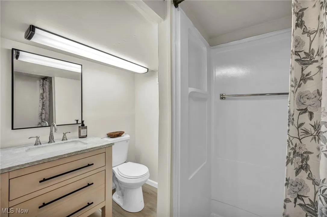 Bathroom with vanity, wood finished floors, and curtained shower