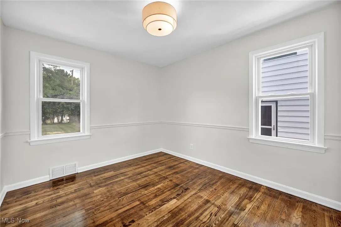 Empty room with dark wood-type flooring and plenty of natural light