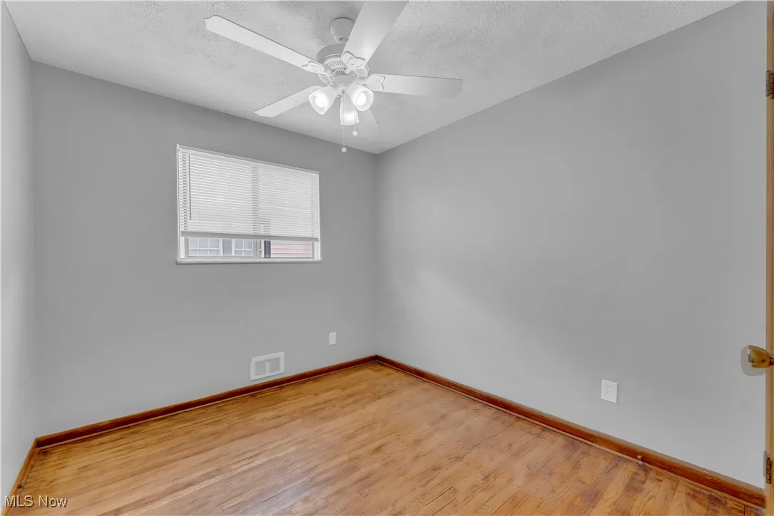 Unfurnished room featuring light wood-style floors, a textured ceiling, and ceiling fan