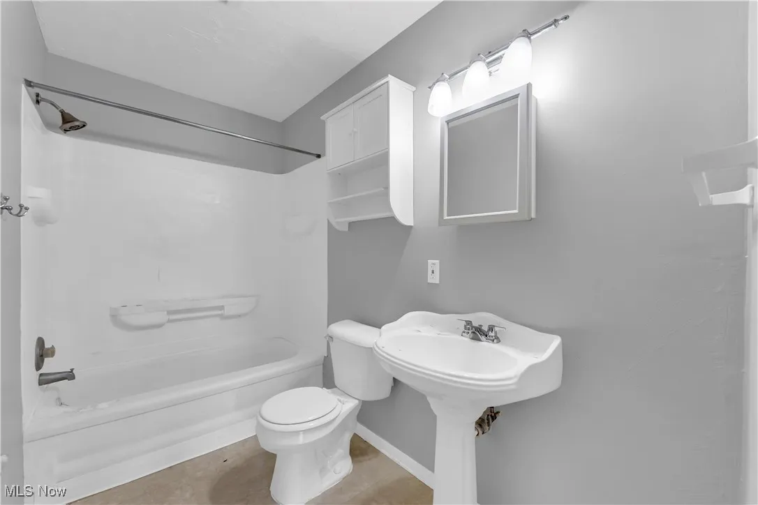 Bathroom with tile patterned flooring and washtub / shower combination