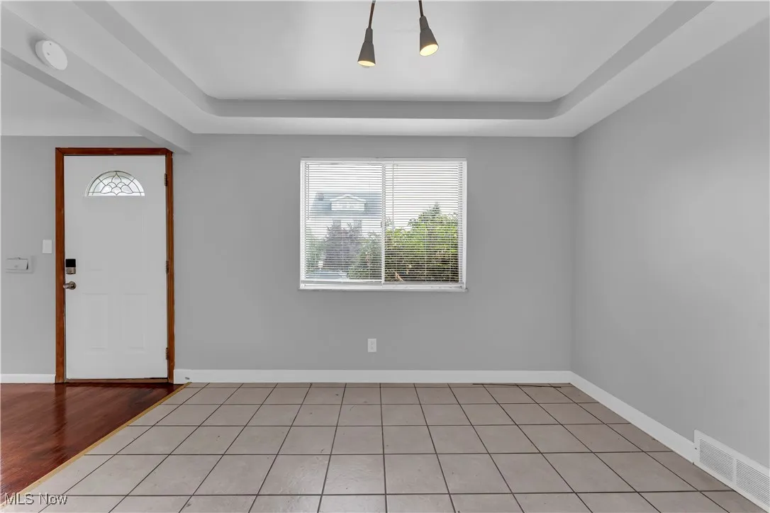 Foyer entrance featuring light tile patterned floors and a tray ceiling