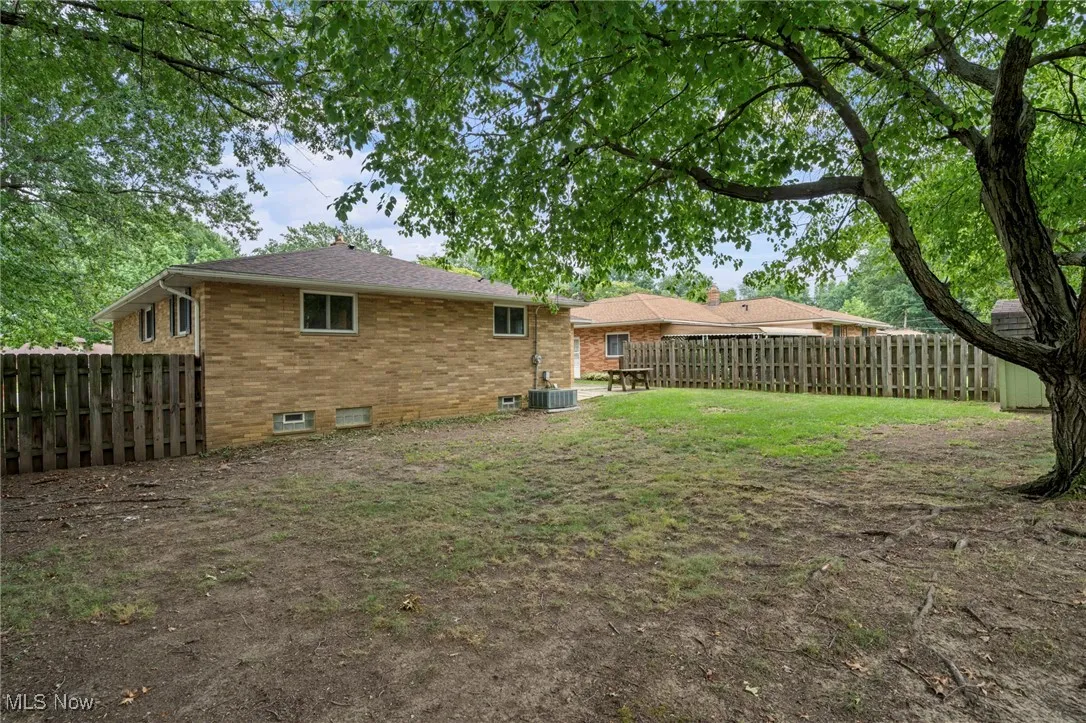 Back of property with brick siding and a fenced backyard