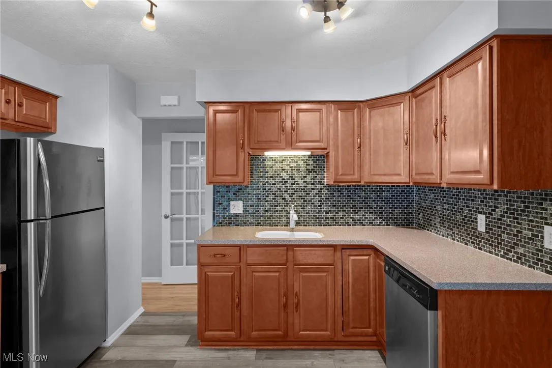 Kitchen featuring stainless steel appliances, backsplash, light wood-style floors, and light countertops