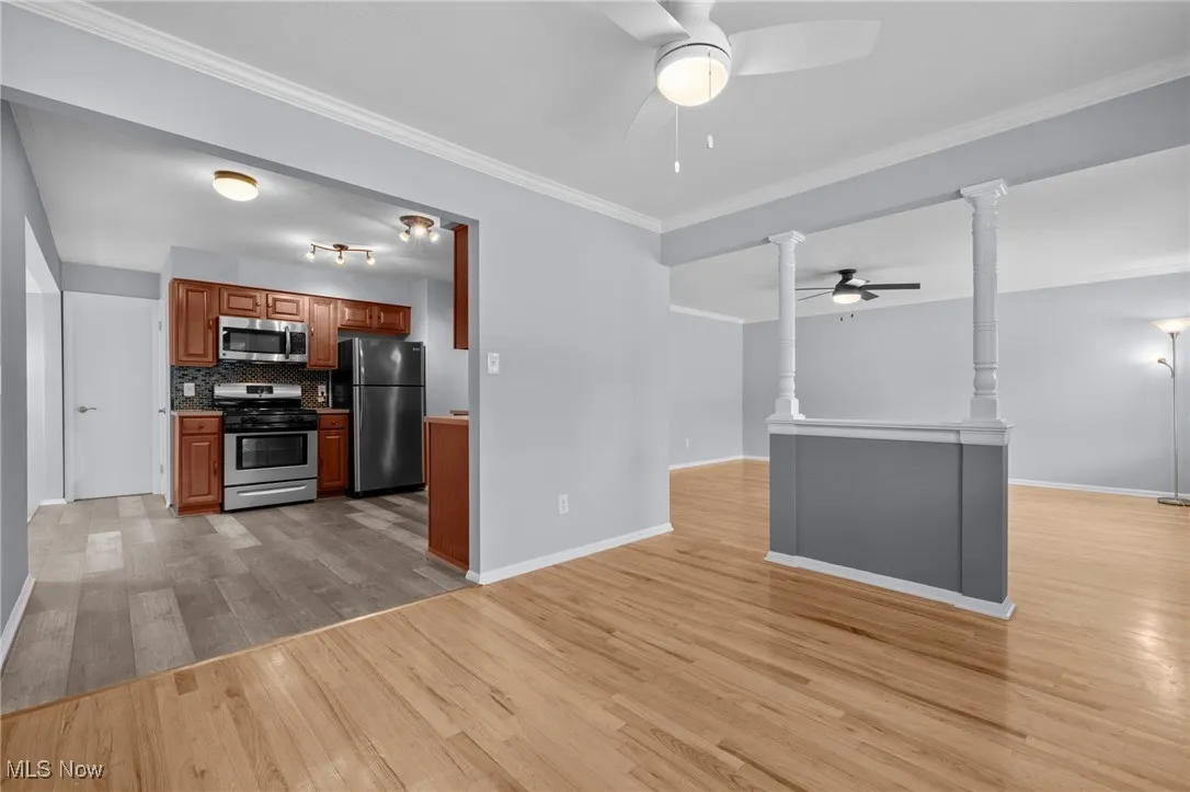 Kitchen featuring ceiling fan, open floor plan, tasteful backsplash, stainless steel appliances, and light wood-style flooring