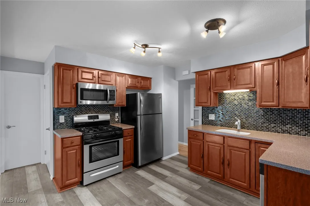 Kitchen with stainless steel appliances, decorative backsplash, and light wood-type flooring
