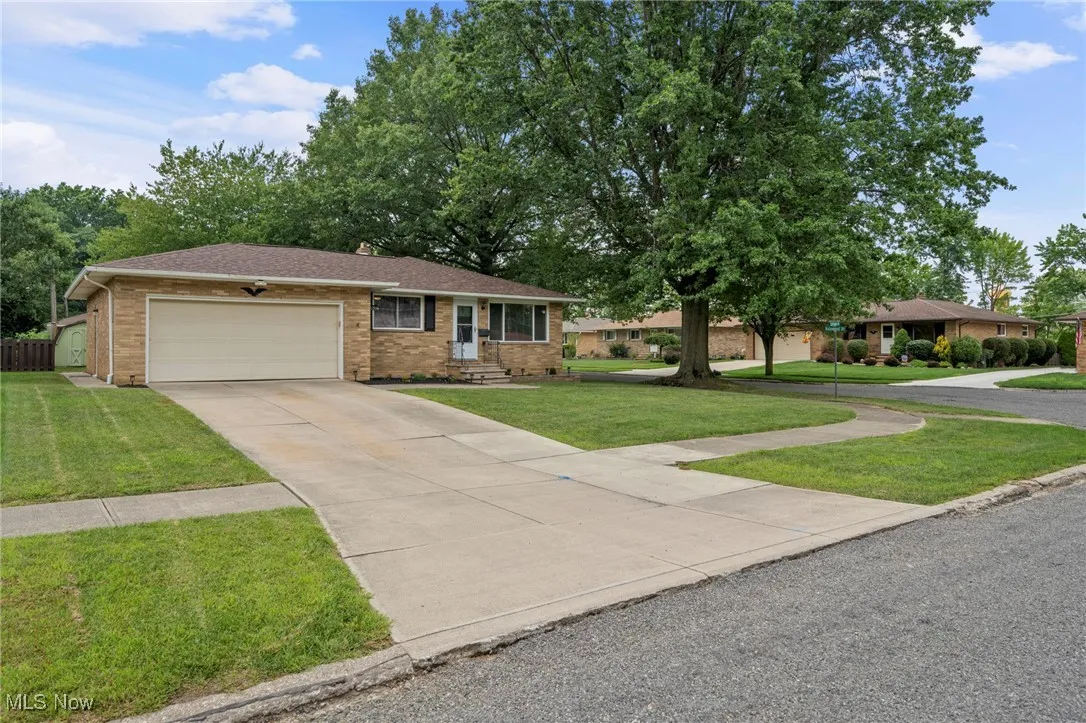 Ranch-style home with concrete driveway, brick siding, a garage, and a front yard