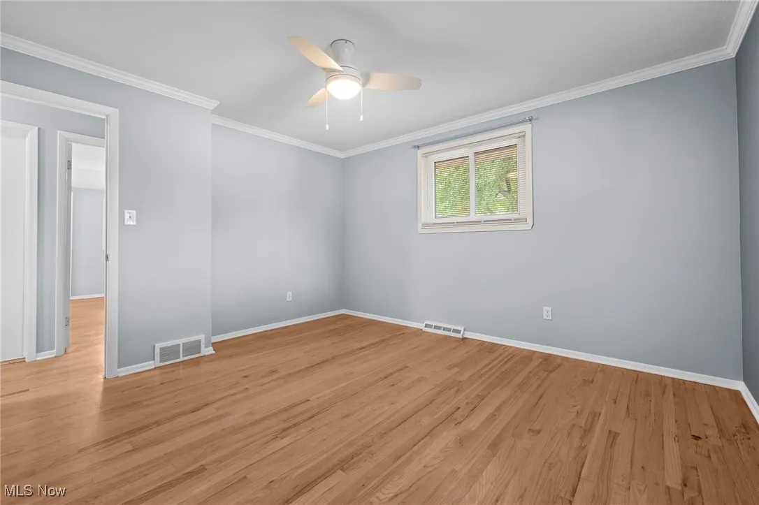 Spare room featuring ornamental molding, light wood finished floors, and a ceiling fan