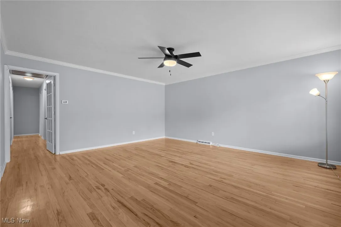 Spare room with light wood-type flooring, crown molding, and ceiling fan