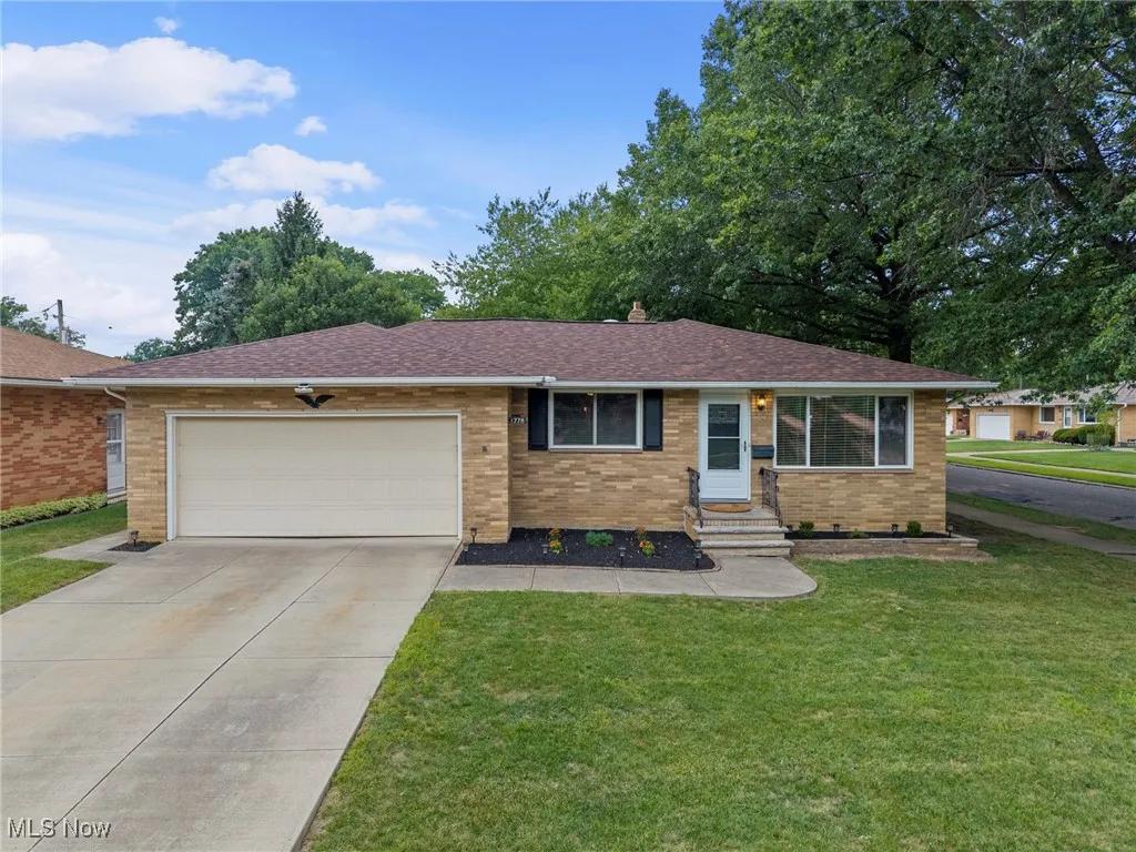Single story home with brick siding, a shingled roof, a front yard, an attached garage, and entry steps