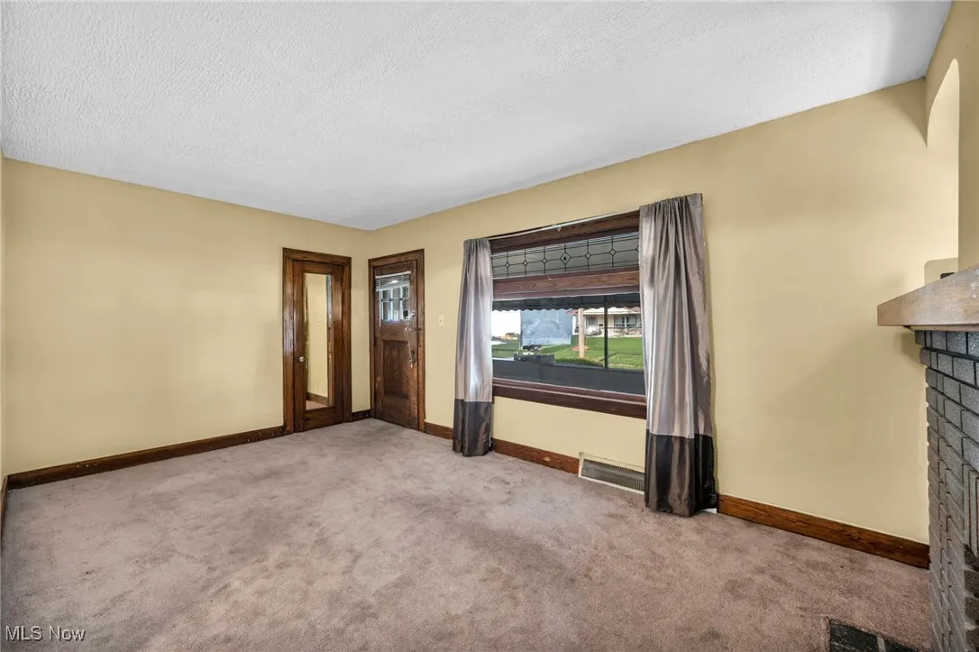 Carpeted living room with a textured ceiling and a decorative fireplace.