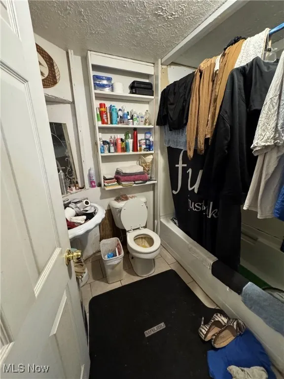 Bathroom with tile patterned floors, a textured ceiling, and shower / bath combo with shower curtain