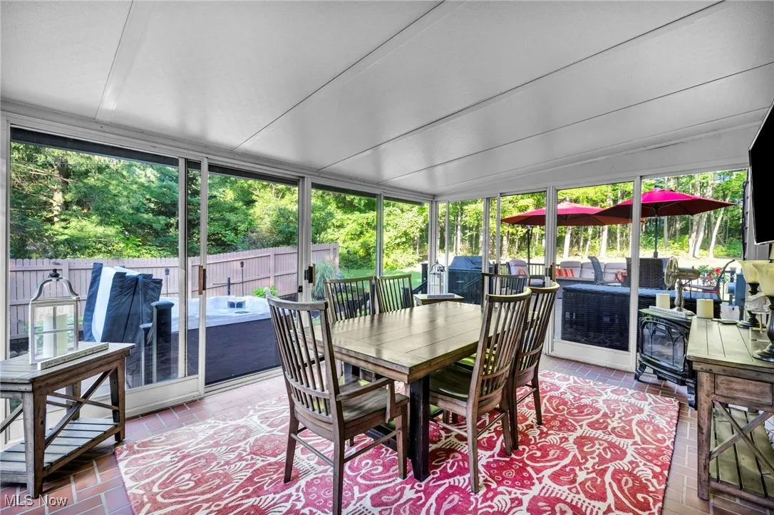 Sunroom featuring plenty of natural light, outdoor lounge area, lofted ceiling, a wood stove, and outdoor dining space