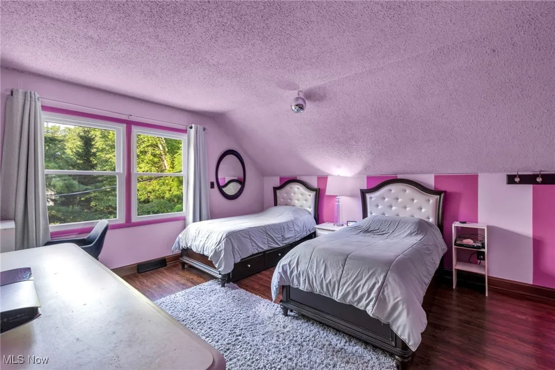 Bedroom with a textured ceiling, vaulted ceiling, and wood finished floors