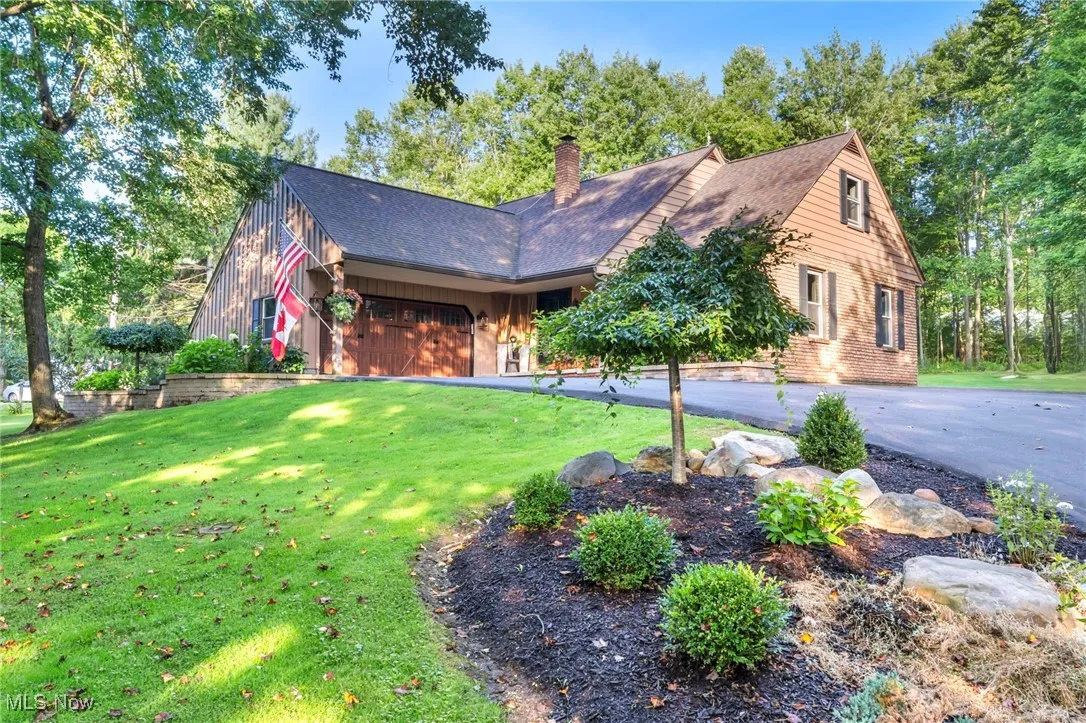 View of front of home with a chimney, a front yard, asphalt driveway, board and batten siding, and a shingled roof