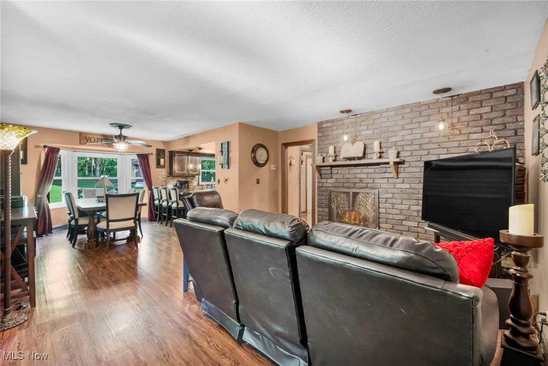 Living room featuring wood finished floors, a brick fireplace, and a textured ceiling