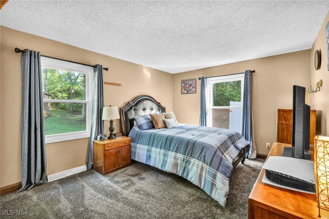 Carpeted bedroom with a textured ceiling and baseboards