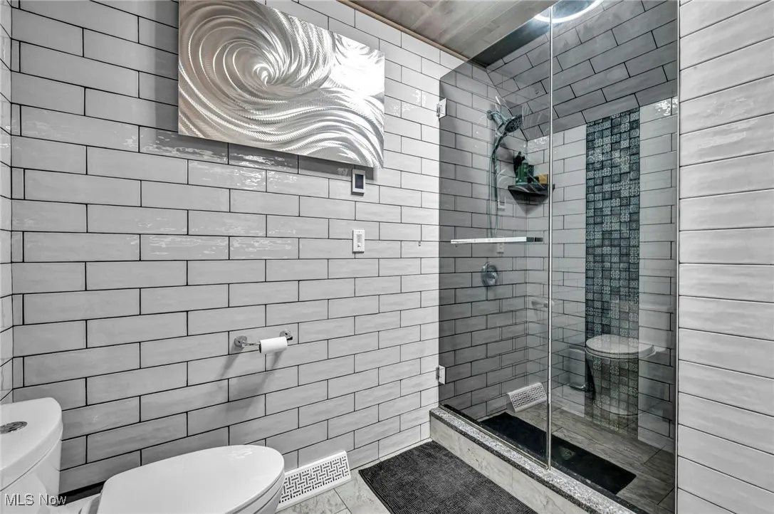 Bathroom featuring tile walls and a stall shower