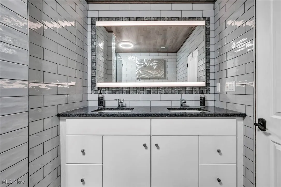 Bathroom featuring tile walls and double vanity