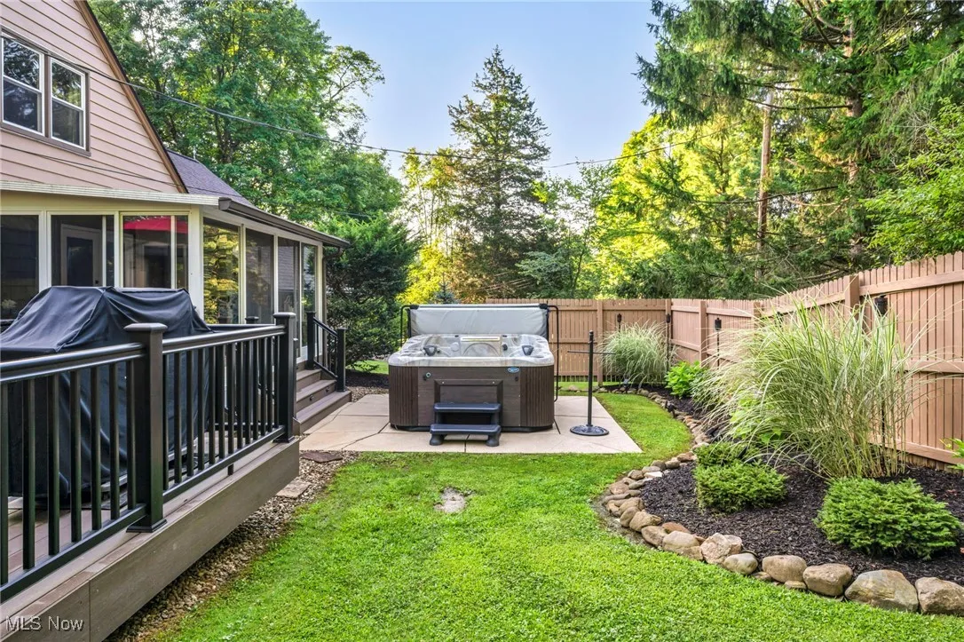 Fenced backyard featuring a hot tub, a patio area, and a sunroom