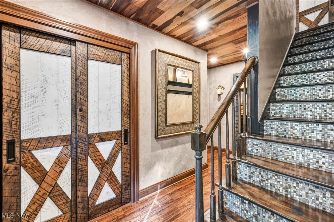 Stairway with wood ceiling, wood finished floors, a textured wall, and recessed lighting