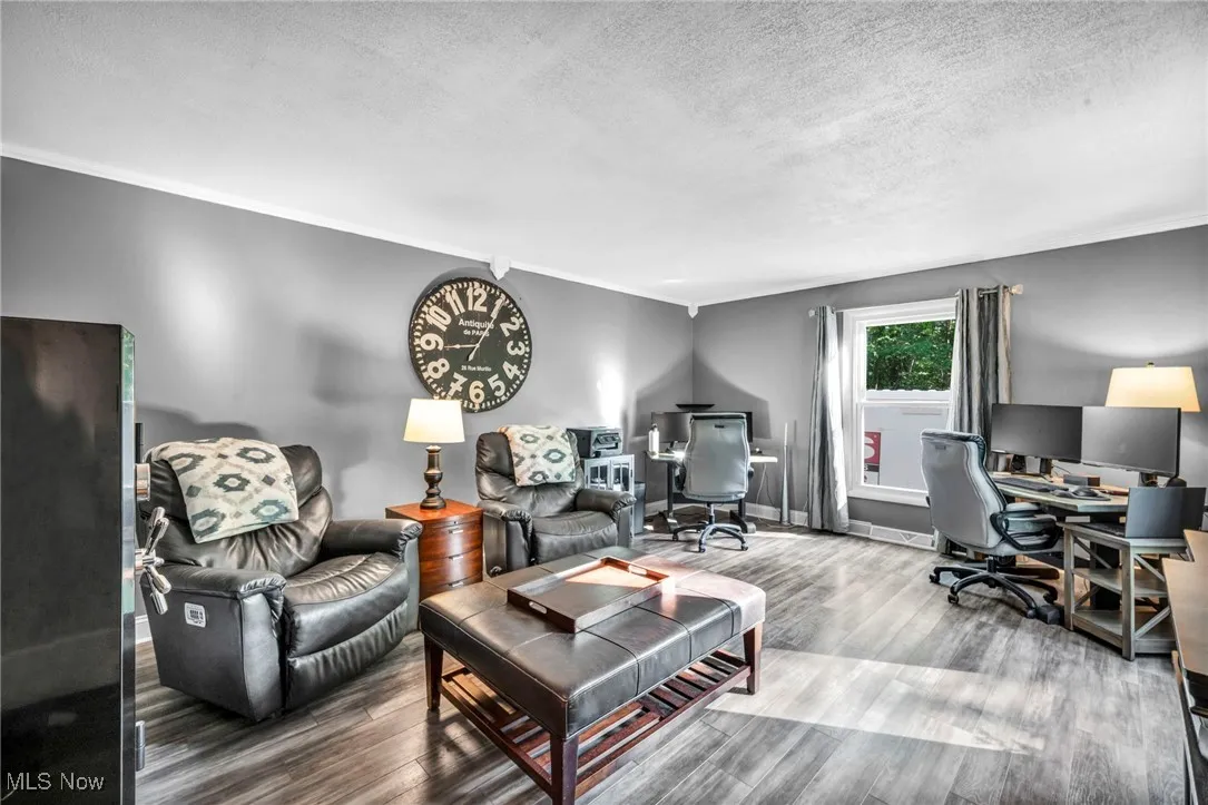 Living room featuring ornamental molding, an office area, wood finished floors, and a textured ceiling