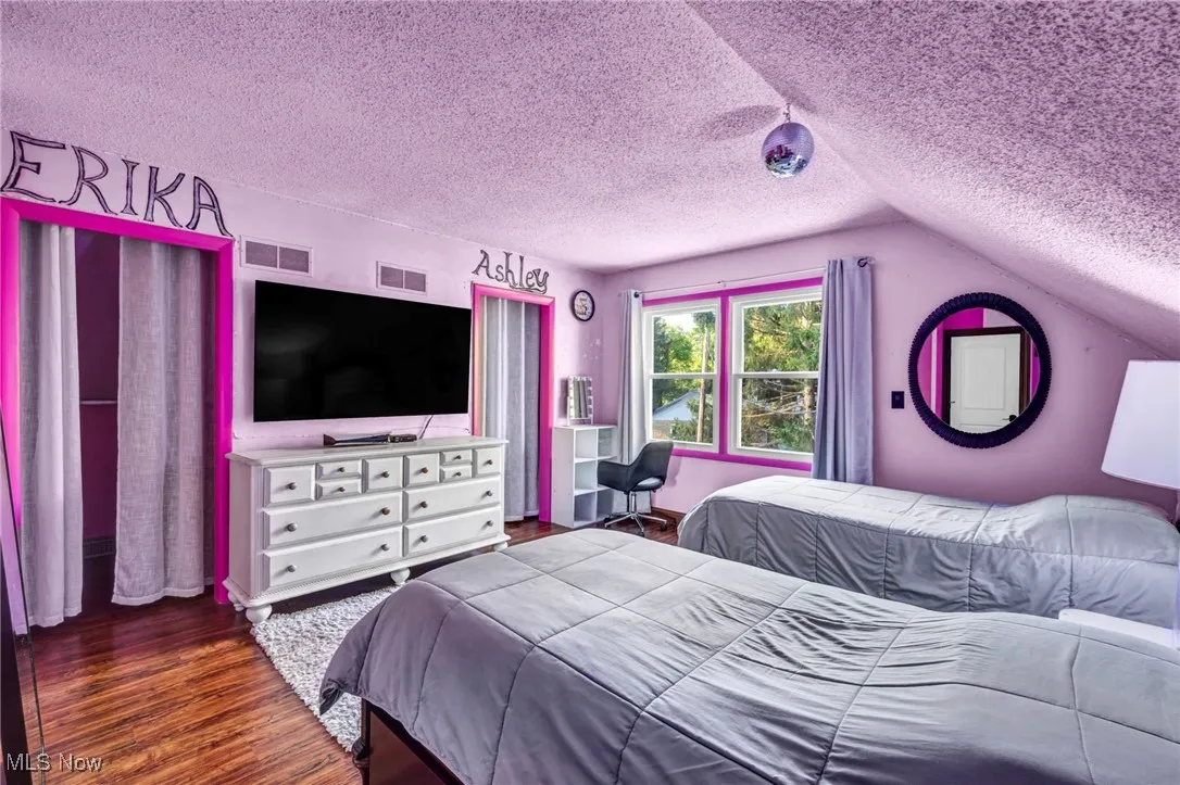Bedroom featuring a textured ceiling, wood finished floors, and lofted ceiling