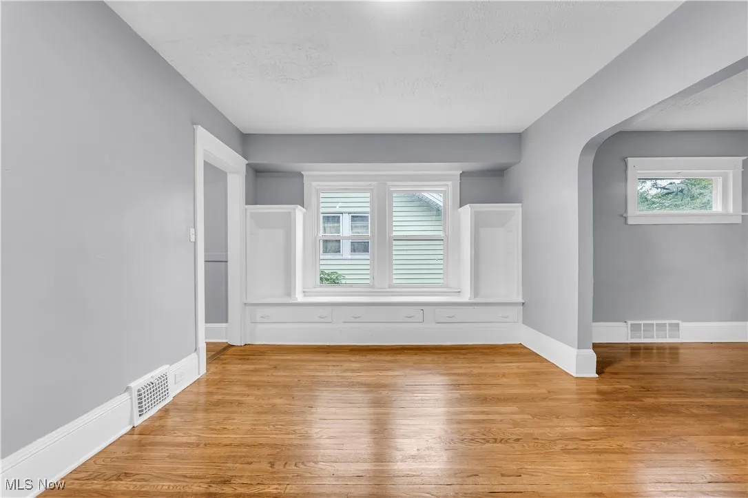 Unfurnished room with arched walkways, wood finished floors, and a textured ceiling