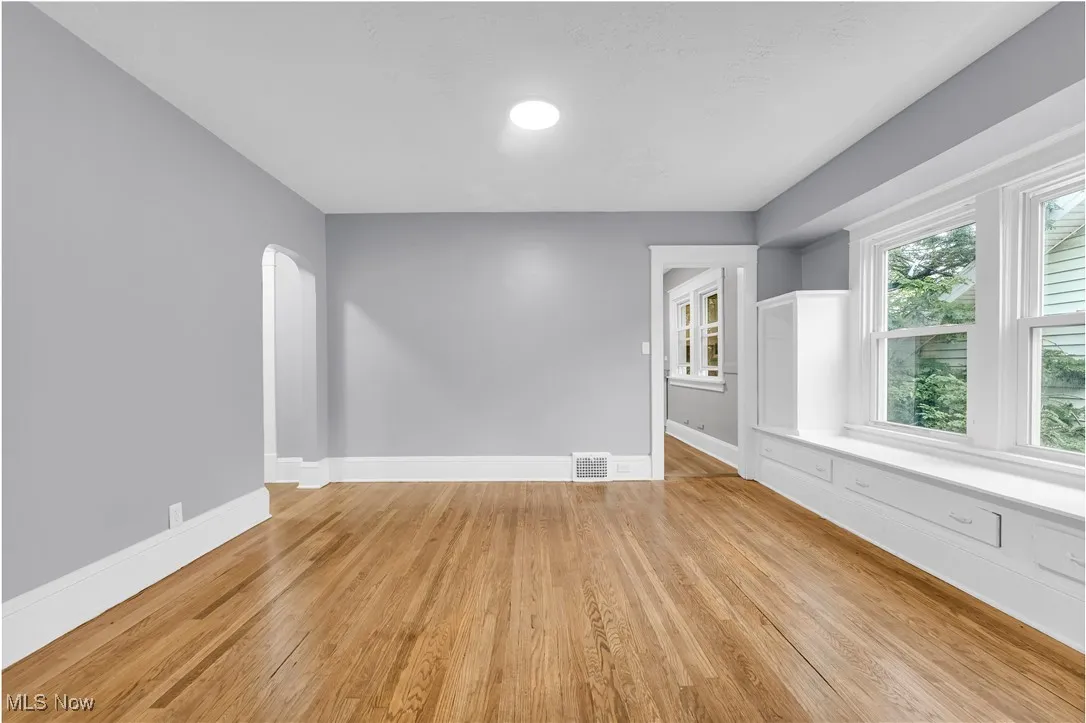 Empty room with arched walkways and light wood-style flooring