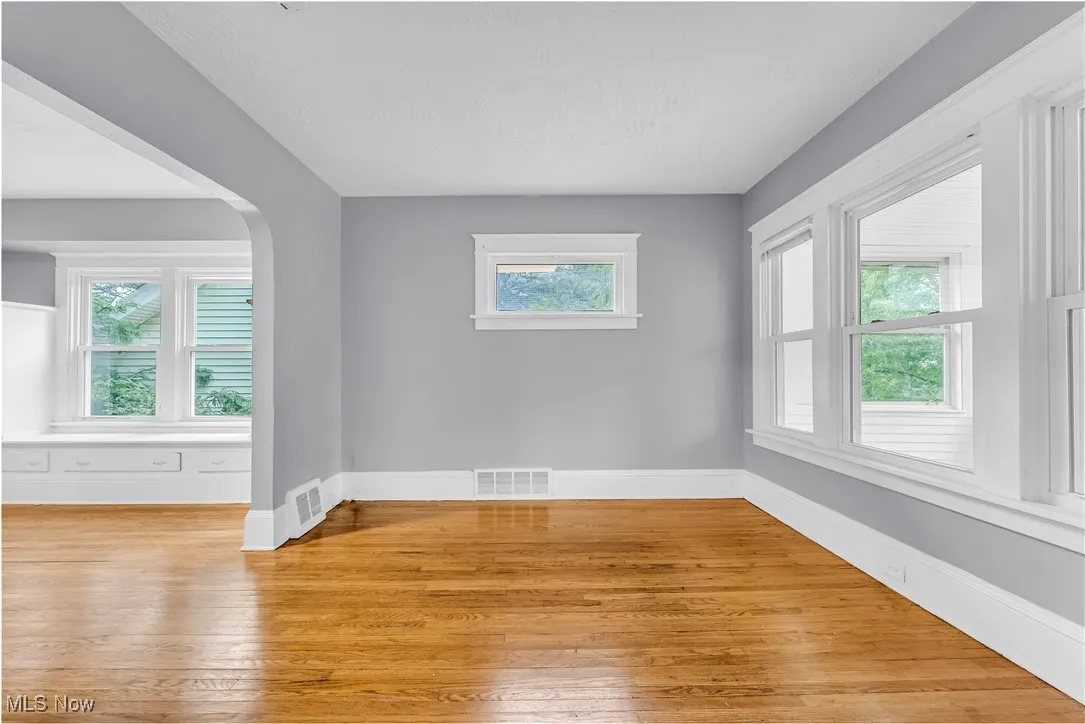 Empty room with arched walkways and light wood-type flooring