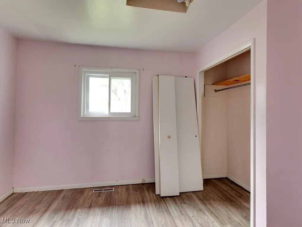 Unfurnished bedroom featuring wood finished floors and a closet