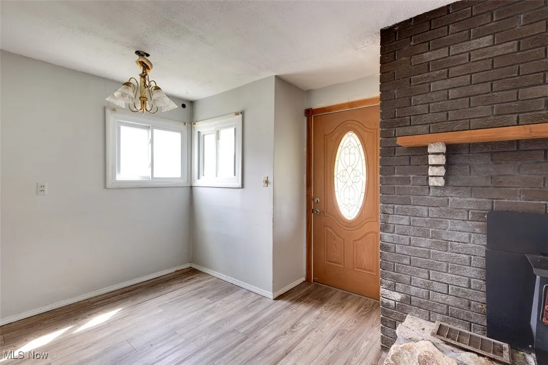 Entryway featuring light wood finished floors, a chandelier, a textured ceiling, and a wood stove
