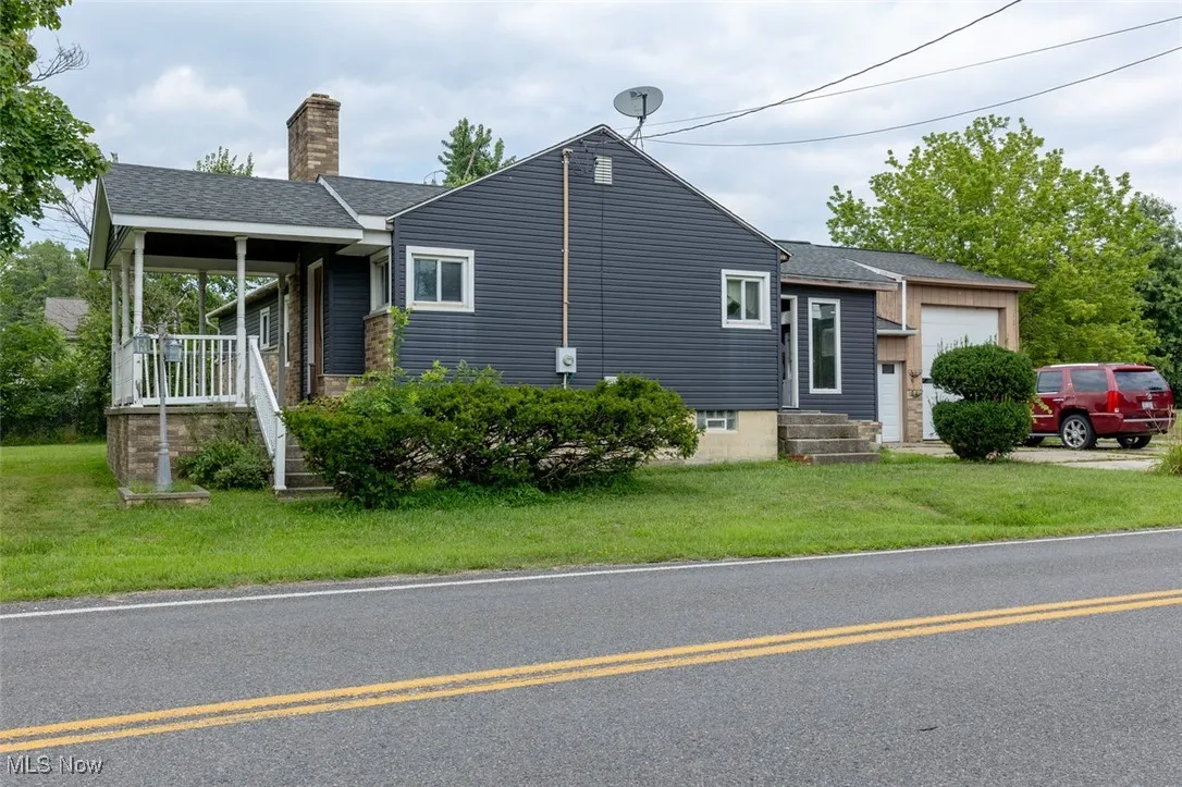 View of front of property with an attached garage, a chimney, a shingled roof, and a front​​‌​​​​‌​​‌‌​‌‌​​​‌‌​‌​‌​‌​​​‌​​ yard