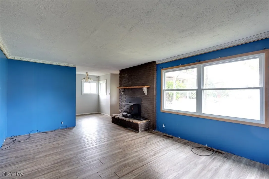 Unfurnished living room with a textured ceiling, wood finished floors, a chandelier, and a fireplace