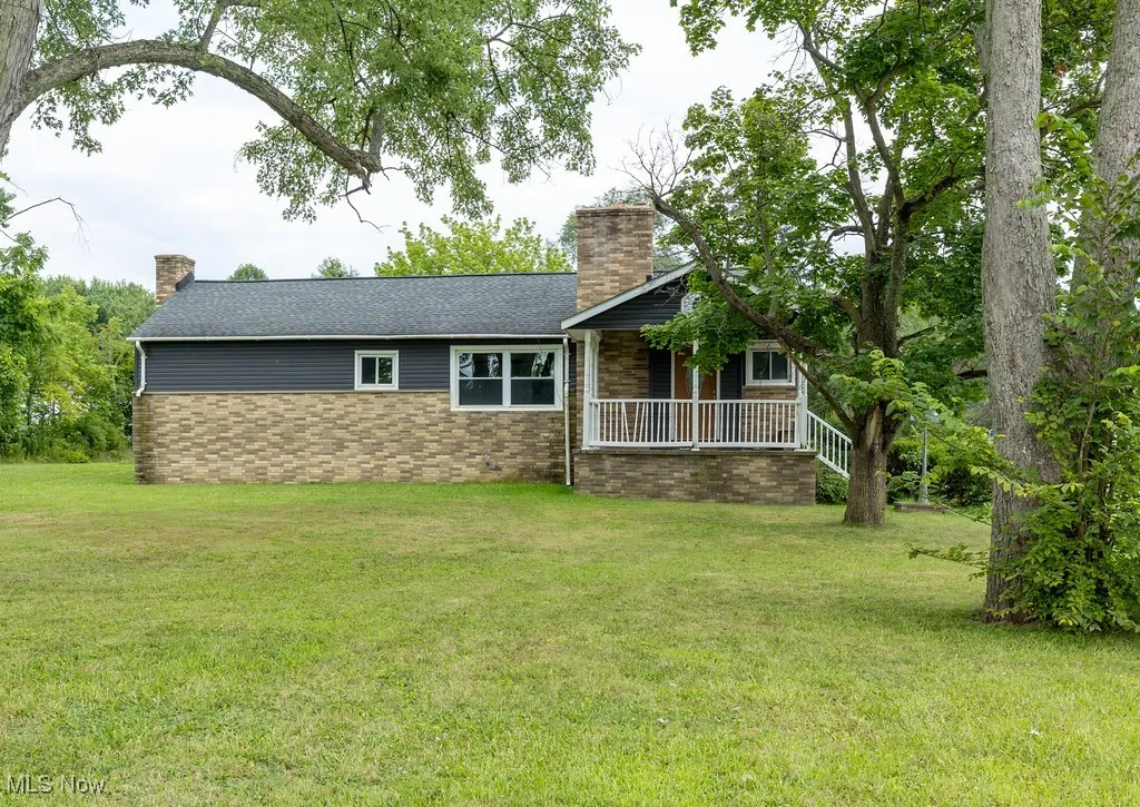Rear view of house with a chimney, a yard, and brick siding