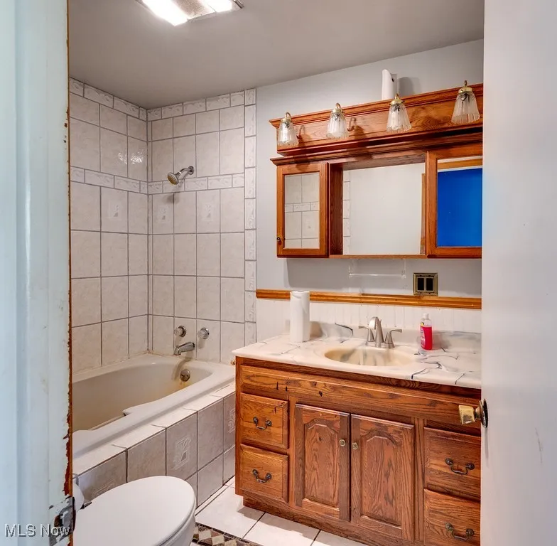 Bathroom with vanity, tile patterned floors, and tiled shower / bath combo