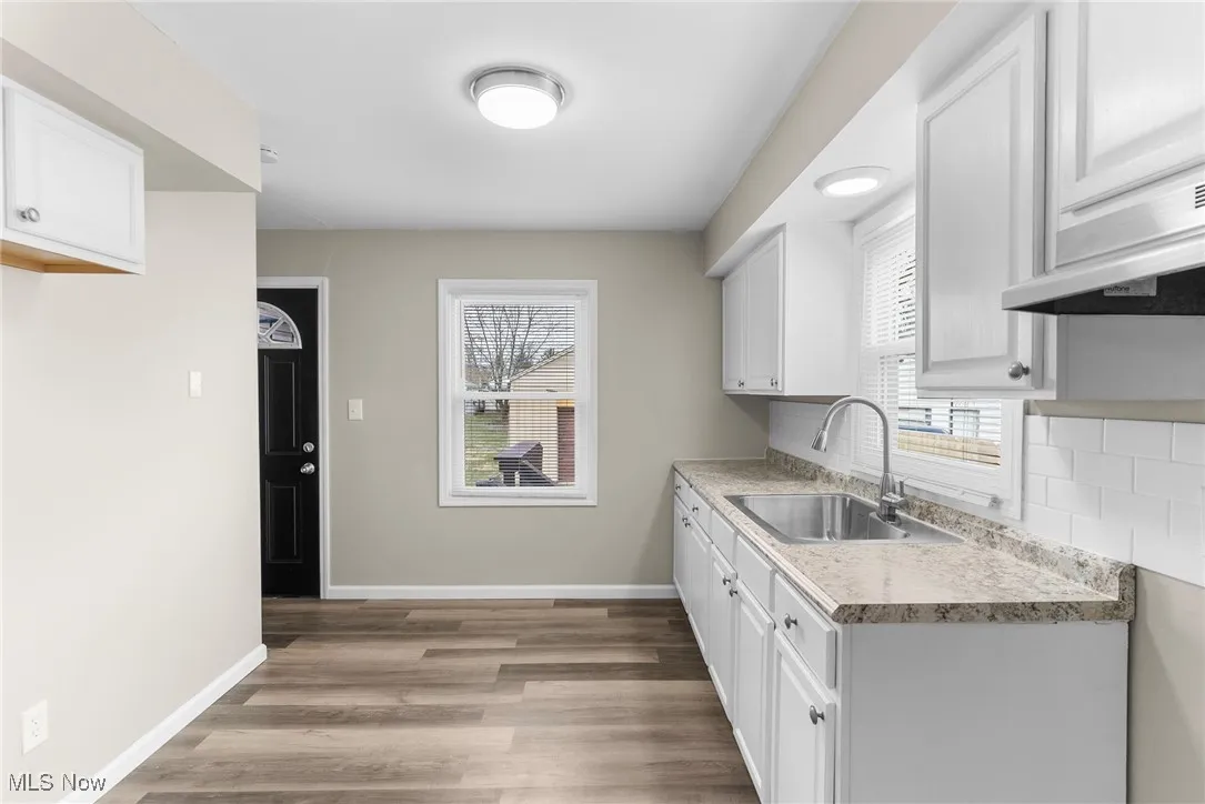 Kitchen with baseboards, light countertops, a sink, and backsplash